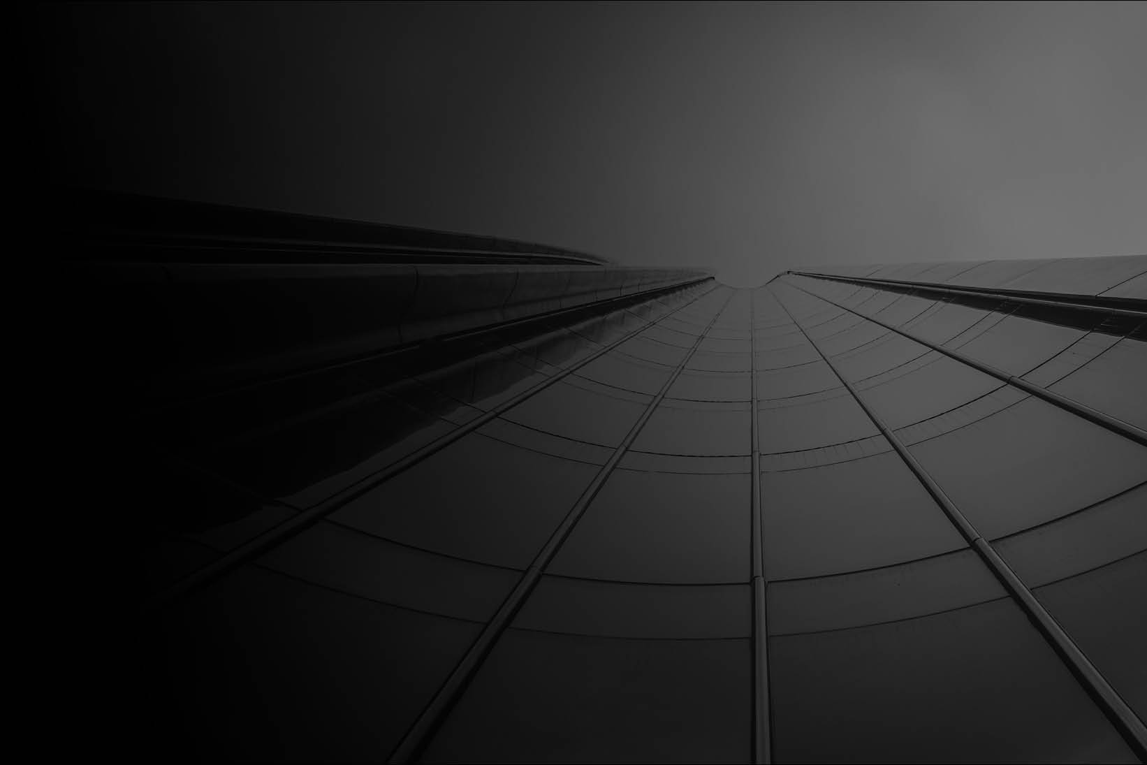 Low-angle view of a modern glass skyscraper rising toward the sky, symbolizing scale, resilience, and market growth - Used on Capco Capital Markets