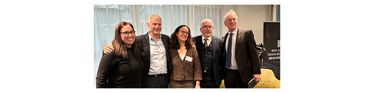 Five professionals posing together at a Capco networking event in a modern conference space