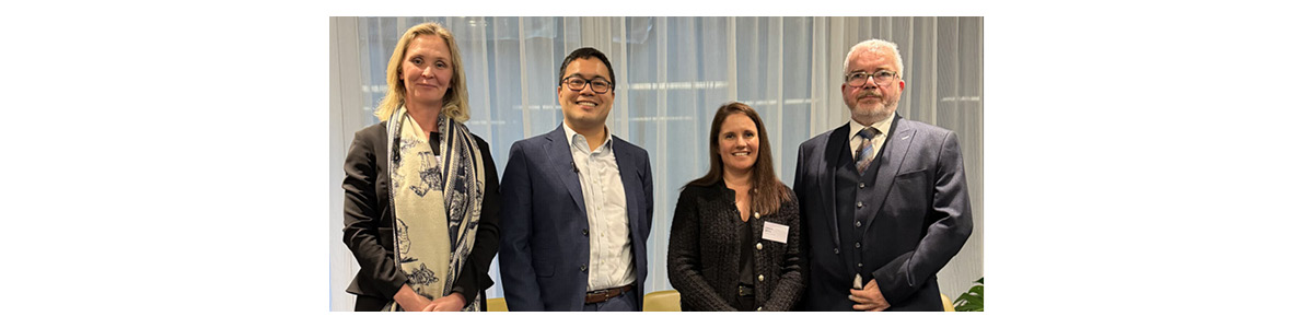 Four attendees posing at a Capco corporate event with conference backdrop